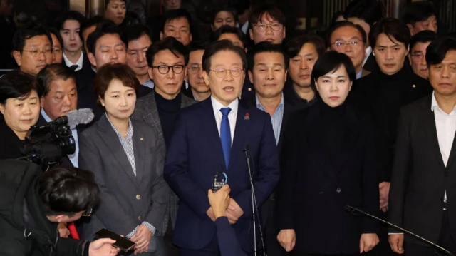 The leader of a key opposition party, the Democratic Party, stands with several other lawmakers while addressing media after parliament voted down martial law on Wednesday morning